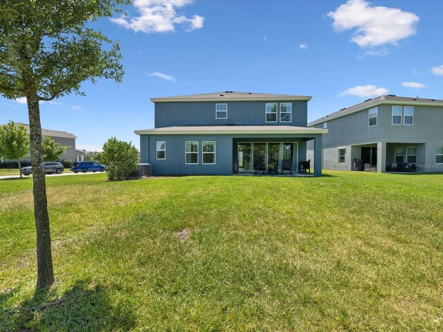 back of property featuring a lawn, stucco siding, and cooling unit