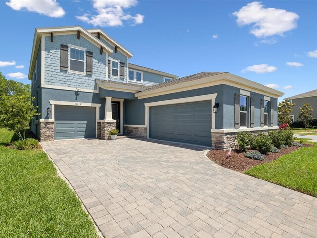 view of front of property featuring stucco siding, an attached garage, decorative driveway, and stone siding