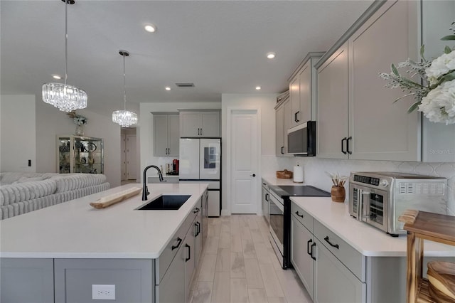 6252 Hidden Branch Dr, Apollo Beach, FL 33572 - kitchen with a sink, visible vents, white refrigerator, electric stove, and gray cabinetry