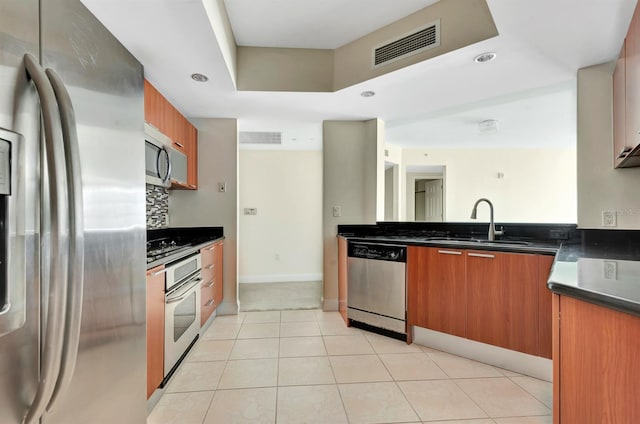 241 Riverside Dr Unit 1107, Daytona Beach, FL 32117 - kitchen featuring brown cabinetry, stainless steel appliances, dark countertops, a sink, and visible vents