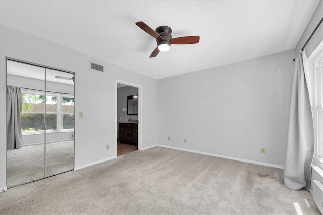 2231 Utopian Dr E Unit 117, Clearwater, FL 33763 - unfurnished bedroom with carpet floors, baseboards, ensuite bathroom, a ceiling fan, and a textured ceiling
