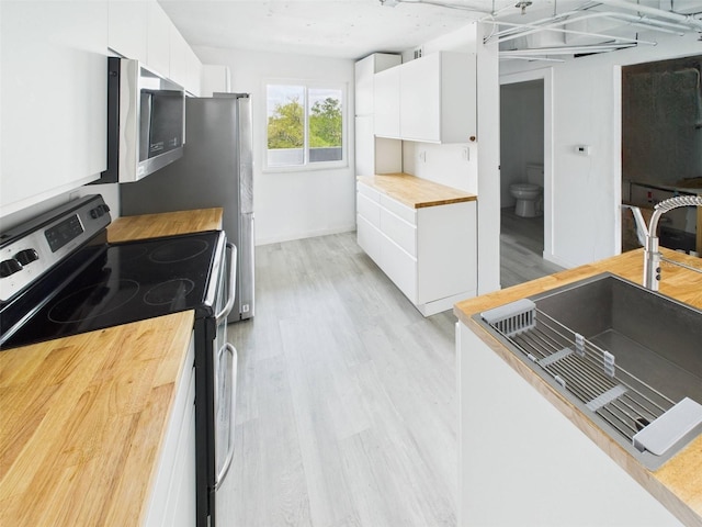 201 W Laurel St Unit 504B, Tampa, FL 33602 - kitchen featuring butcher block countertops, appliances with stainless steel finishes, white cabinets, modern cabinets, and light wood finished floors