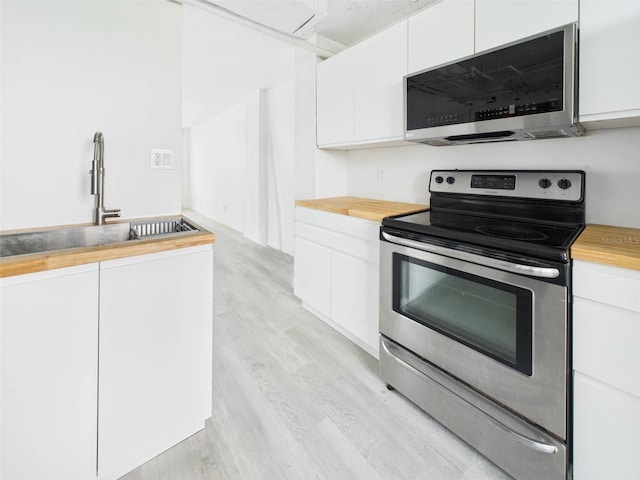 201 W Laurel St Unit 504B, Tampa, FL 33602 - kitchen with stainless steel appliances, butcher block countertops, white cabinets, and light wood finished floors