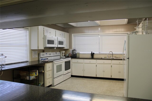 9950 47th Ave N Unit 311, Saint Petersburg, FL 33708 - kitchen with dark countertops, white appliances, white cabinets, and a sink
