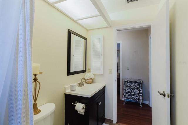 bathroom with vanity, wood finished floors, visible vents, and toilet