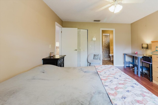 bedroom featuring visible vents, a closet, wood finished floors, baseboards, and ensuite bathroom