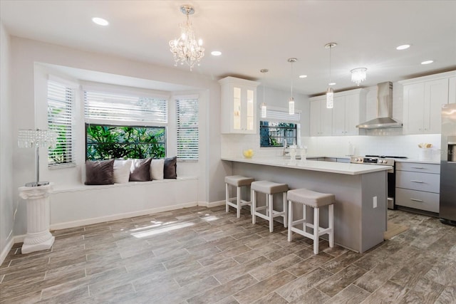 kitchen with wall chimney range hood, decorative backsplash, stainless steel appliances, and a kitchen bar