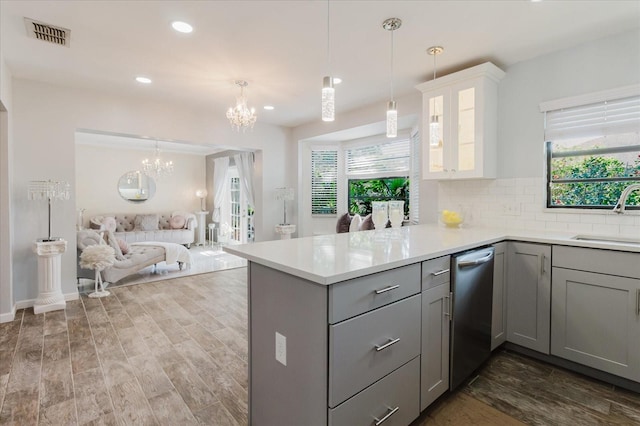 kitchen with a sink, light countertops, a chandelier, a peninsula, and gray cabinetry