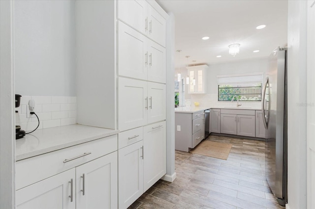 kitchen with tasteful backsplash, a sink, white cabinets, stainless steel appliances, and recessed lighting