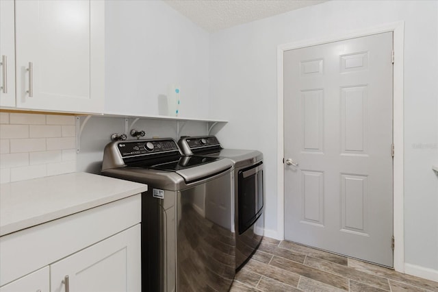 washroom featuring baseboards, wood finish floors, a textured ceiling, cabinet space, and independent washer and dryer