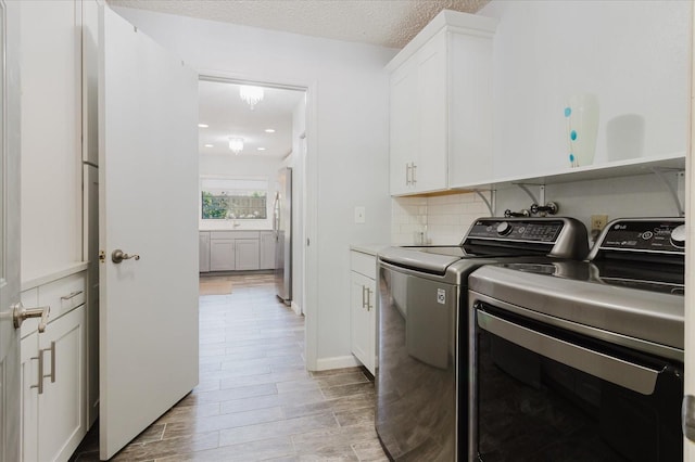 washroom with cabinet space, light wood finished floors, and washing machine and dryer