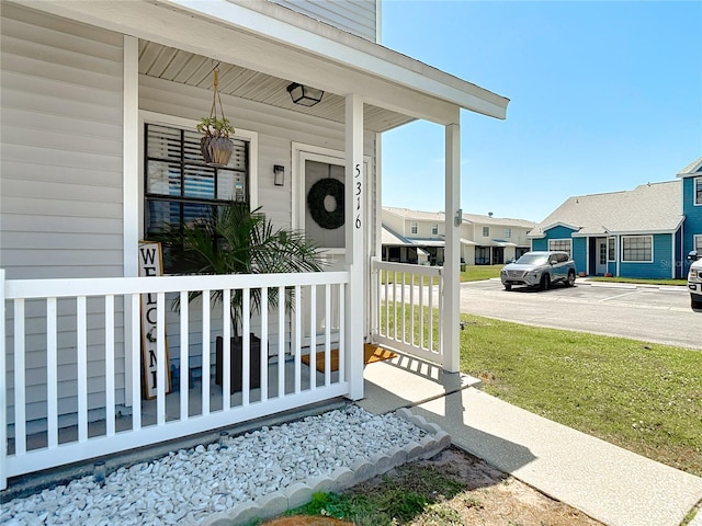 view of exterior entry featuring a porch, uncovered parking, and a residential view