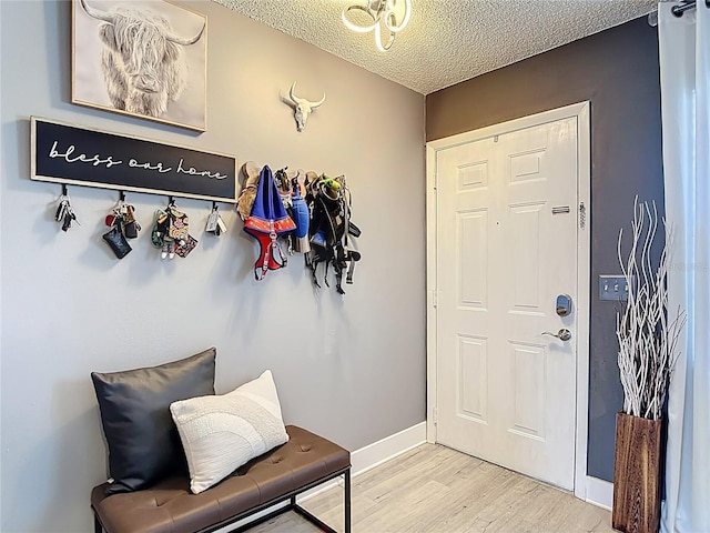 entryway featuring a textured ceiling, light wood-style floors, and baseboards
