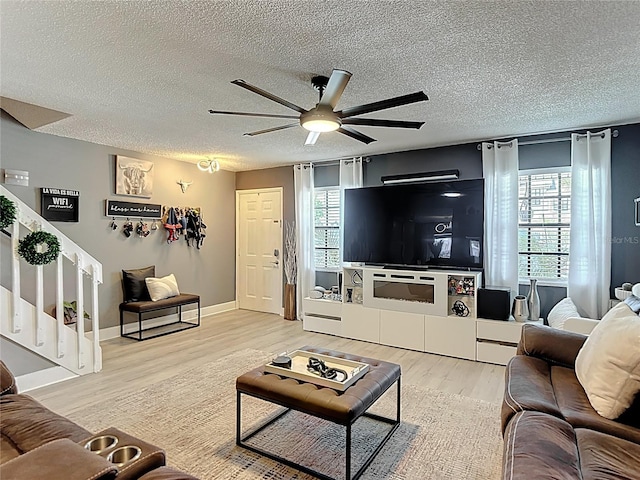 living room with stairway, ceiling fan, a textured ceiling, and light wood finished floors