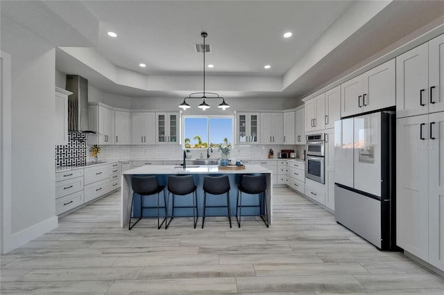 935 Chipaway Dr, Apollo Beach, FL 33572 - kitchen featuring fridge, wall chimney range hood, a raised ceiling, a breakfast bar, and a center island with sink