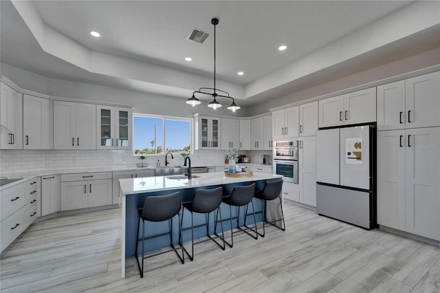 935 Chipaway Dr, Apollo Beach, FL 33572 - kitchen featuring freestanding refrigerator, a raised ceiling, double oven, a kitchen island with sink, and a breakfast bar