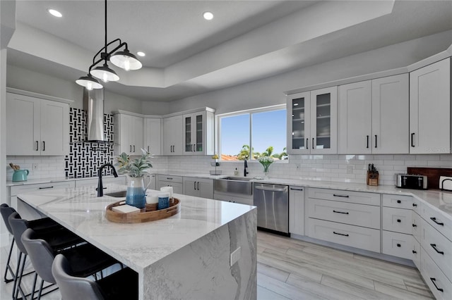 935 Chipaway Dr, Apollo Beach, FL 33572 - kitchen with stainless steel dishwasher, light stone countertops, an island with sink, wall chimney range hood, and a kitchen breakfast bar