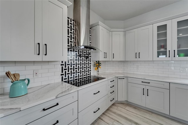 935 Chipaway Dr, Apollo Beach, FL 33572 - kitchen with black electric stovetop, wall chimney range hood, light stone countertops, and backsplash