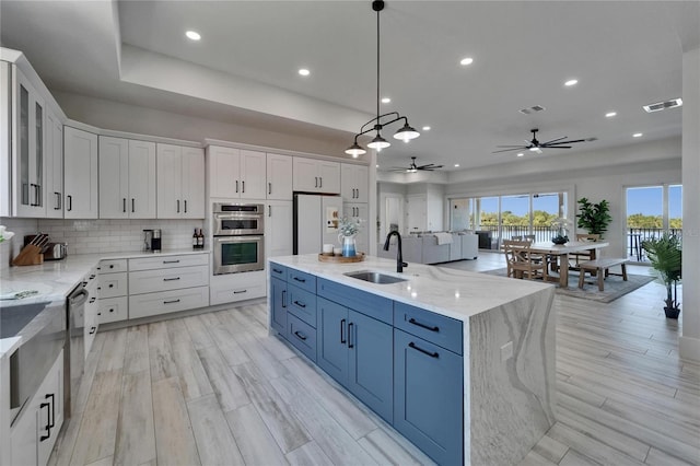 935 Chipaway Dr, Apollo Beach, FL 33572 - kitchen with a sink, appliances with stainless steel finishes, white cabinetry, a ceiling fan, and backsplash