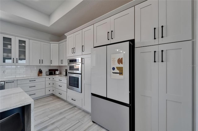 935 Chipaway Dr, Apollo Beach, FL 33572 - kitchen with freestanding refrigerator, stainless steel double oven, white cabinets, glass insert cabinets, and light stone countertops