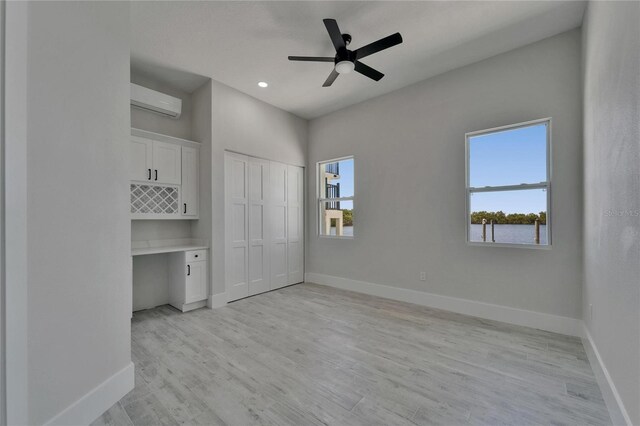 935 Chipaway Dr, Apollo Beach, FL 33572 - unfurnished bedroom with an AC wall unit, baseboards, light wood finished floors, and recessed lighting