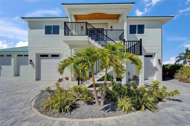 935 Chipaway Dr, Apollo Beach, FL 33572 - view of front facade featuring stairway, stucco siding, an attached garage, decorative driveway, and a balcony
