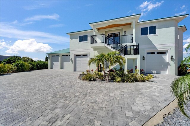 935 Chipaway Dr, Apollo Beach, FL 33572 - view of front of house with stucco siding, stairway, an attached garage, decorative driveway, and a balcony