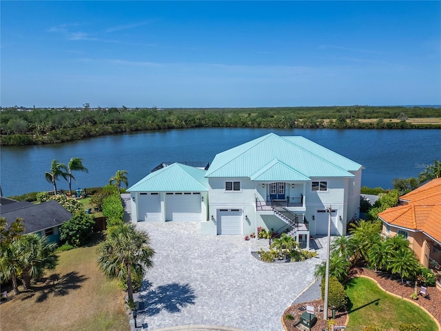 935 Chipaway Dr, Apollo Beach, FL 33572 - coastal inspired home with stairway, a water view, stucco siding, an attached garage, and metal roof