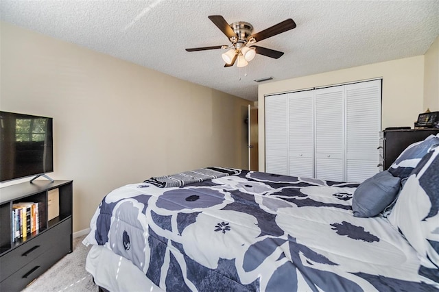 bedroom featuring visible vents, a textured ceiling, carpet floors, and a closet