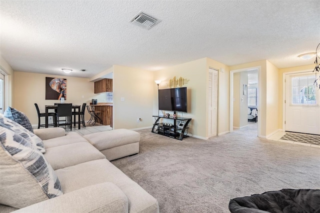 living room with baseboards, carpet, a textured ceiling, and visible vents