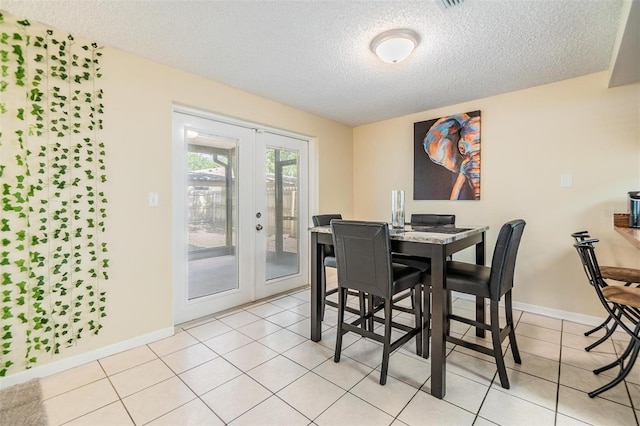 dining room with french doors, a textured ceiling, light tile patterned floors, and baseboards