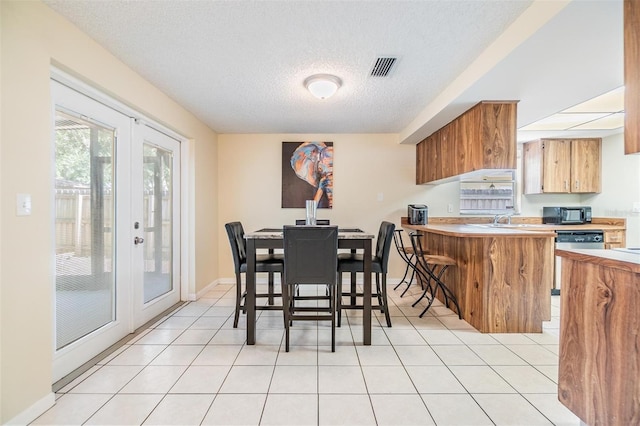 dining space featuring light tile patterned floors, a textured ceiling, visible vents, and french doors