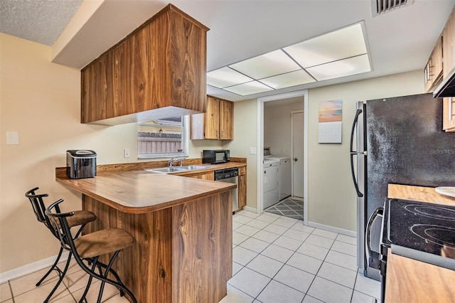 kitchen with visible vents, a peninsula, separate washer and dryer, a sink, and black appliances
