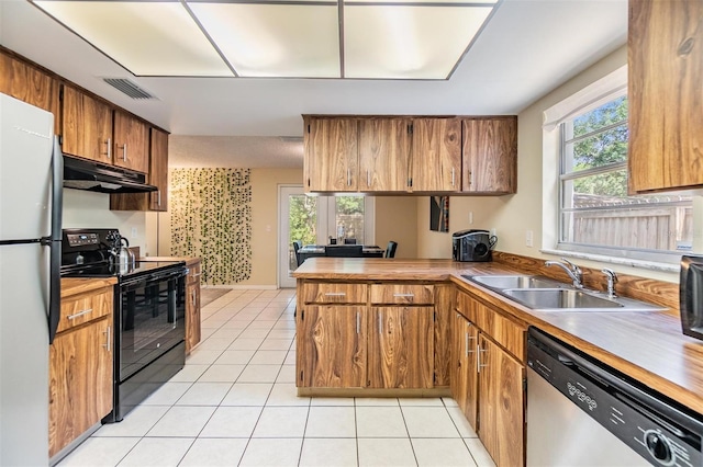 kitchen with stainless steel dishwasher, black range with electric stovetop, a sink, light tile patterned floors, and a peninsula