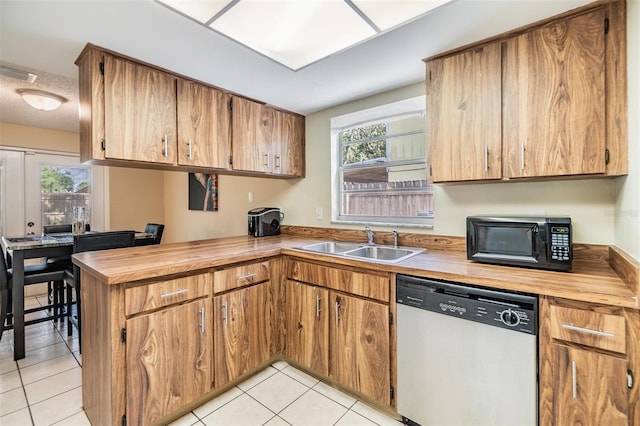 kitchen with black microwave, a sink, dishwasher, a peninsula, and light tile patterned floors