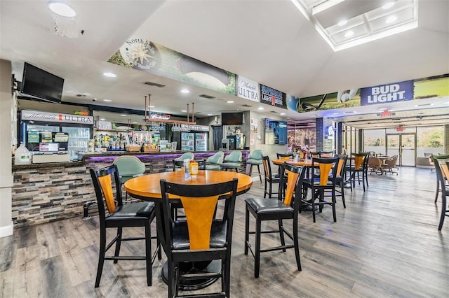 dining room with recessed lighting, vaulted ceiling, wood finished floors, and visible vents