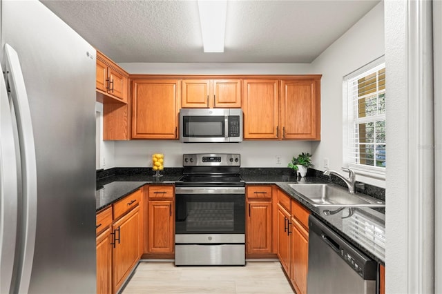 kitchen featuring stainless steel appliances, brown cabinetry, and a sink