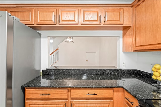 kitchen with freestanding refrigerator, electric range, and dark stone countertops
