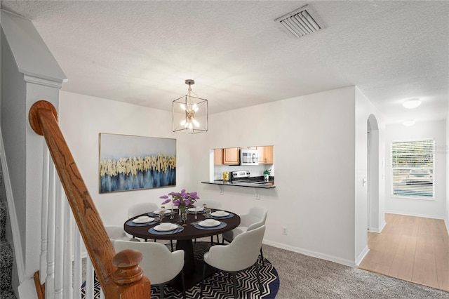 dining space featuring visible vents, baseboards, a textured ceiling, arched walkways, and a notable chandelier