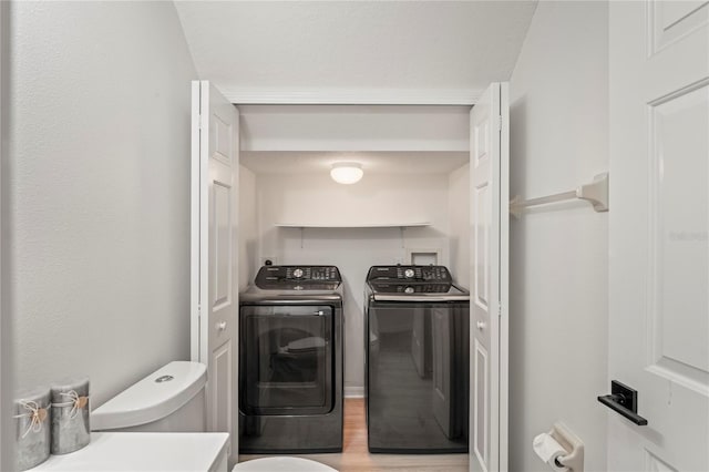 laundry area with laundry area, washer and clothes dryer, and light wood-style floors