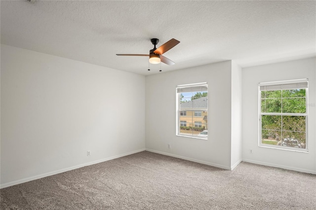 carpeted spare room with baseboards, ceiling fan, and a textured ceiling