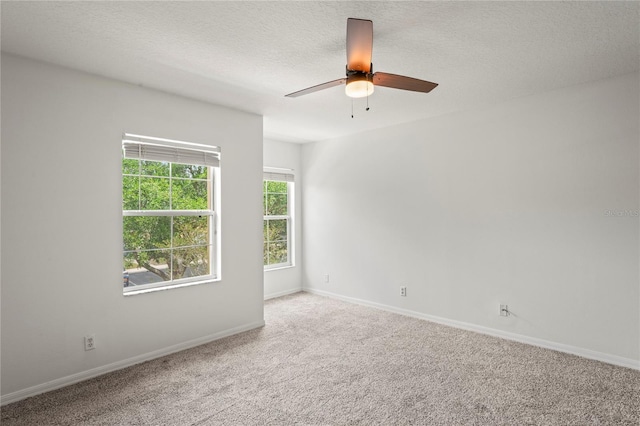 carpeted spare room with baseboards, a ceiling fan, and a textured ceiling