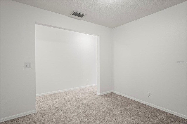 carpeted empty room featuring a textured ceiling, visible vents, and baseboards