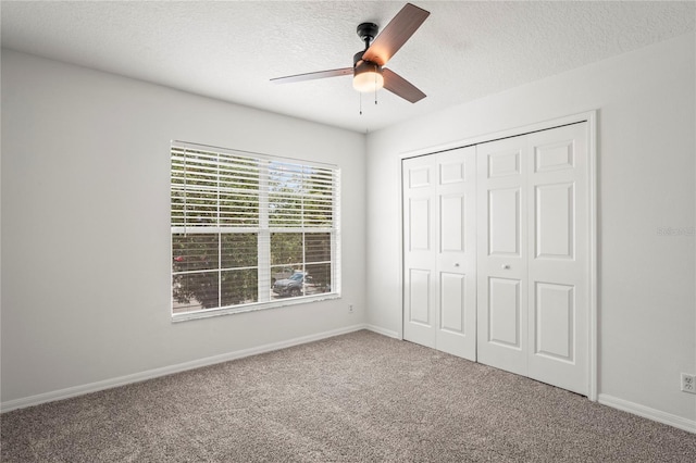 unfurnished bedroom featuring ceiling fan, a textured ceiling, carpet floors, baseboards, and a closet