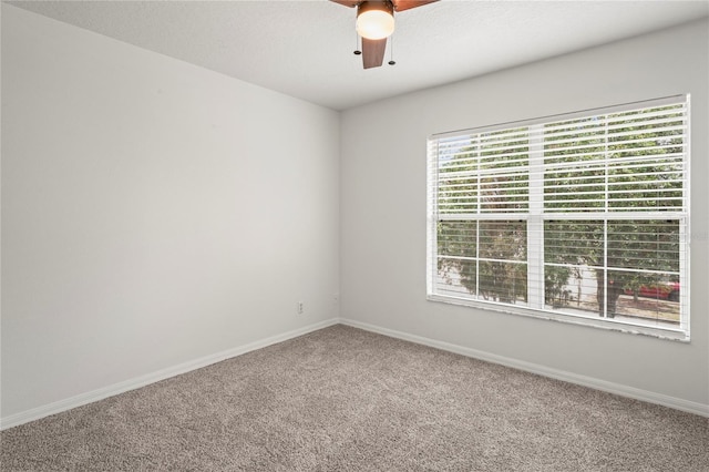 carpeted spare room with a ceiling fan and baseboards