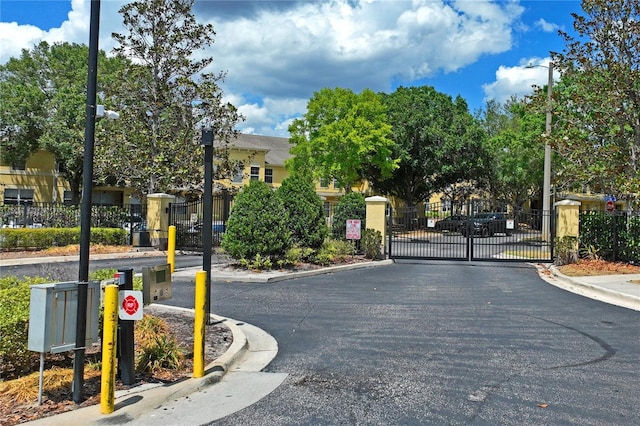 view of street featuring curbs, street lighting, a gated entry, a gate, and traffic signs