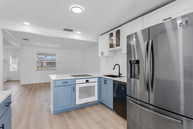 kitchen featuring a sink, visible vents, light wood-style floors, black appliances, and a peninsula