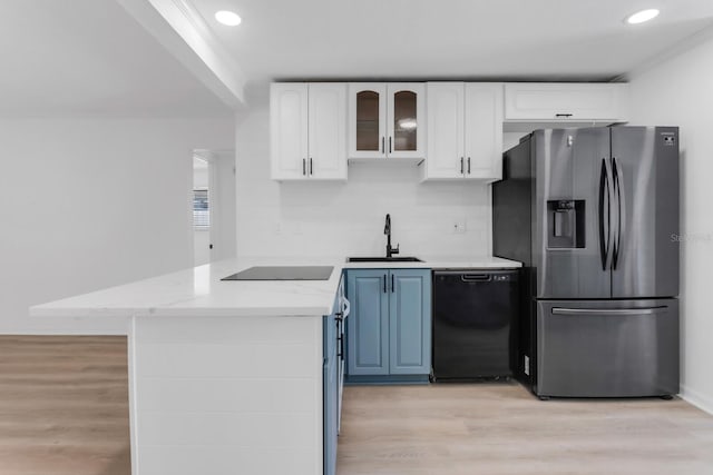 kitchen with light wood-style floors, black appliances, a peninsula, and a sink