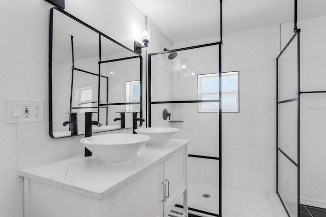 bathroom featuring a shower stall, double vanity, and a sink