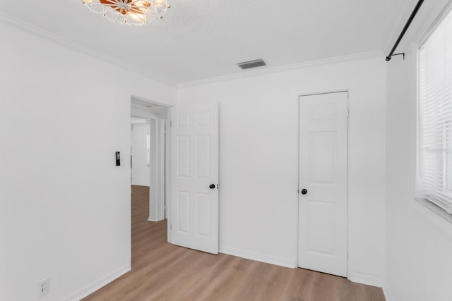 unfurnished bedroom with light wood-style floors, crown molding, visible vents, and baseboards